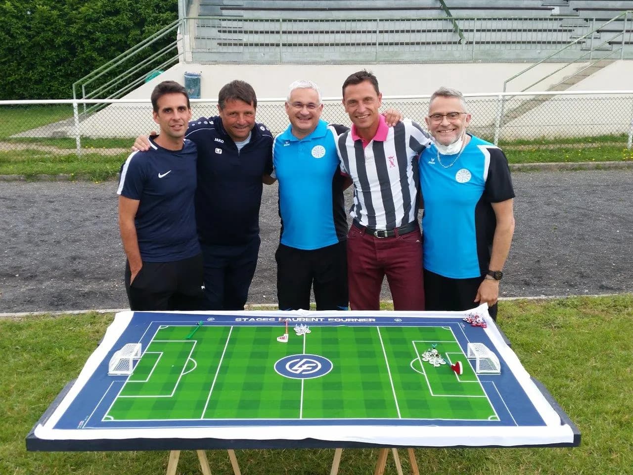 Photo de groupe avec Laurent Fournier derrière un terrain de football de table en plein air