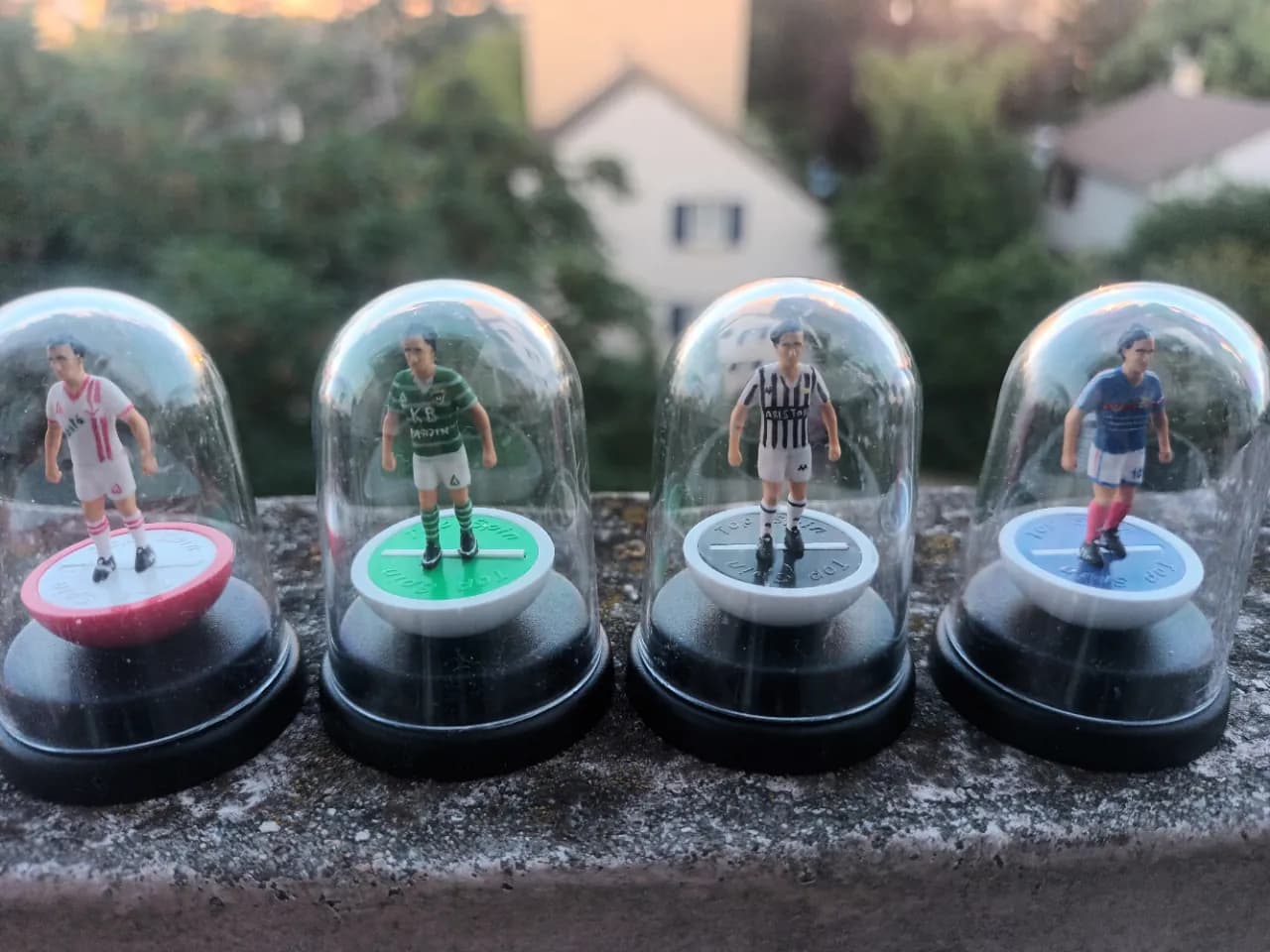 Quatre figurines sous cloche retraçant la carrière de Michel Platini : Nancy, Saint-Étienne, Juventus et équipe de France